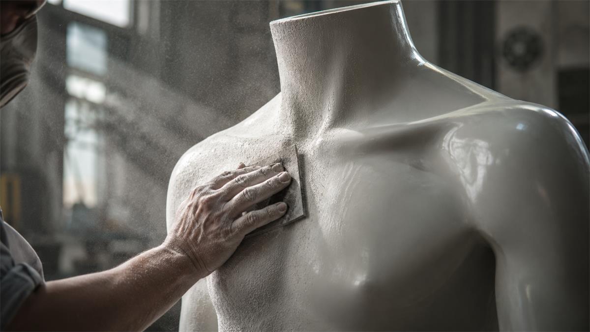 Close-up of fibreglass mannequin manufacturing showing hand-sanding and finishing process in a factory workshop Close-up of fibreglass mannequin manufacturing showing hand-sanding and finishing process in a factory workshop